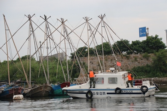 图为饶平县三百门渔港，公安边防在指挥渔船停放。