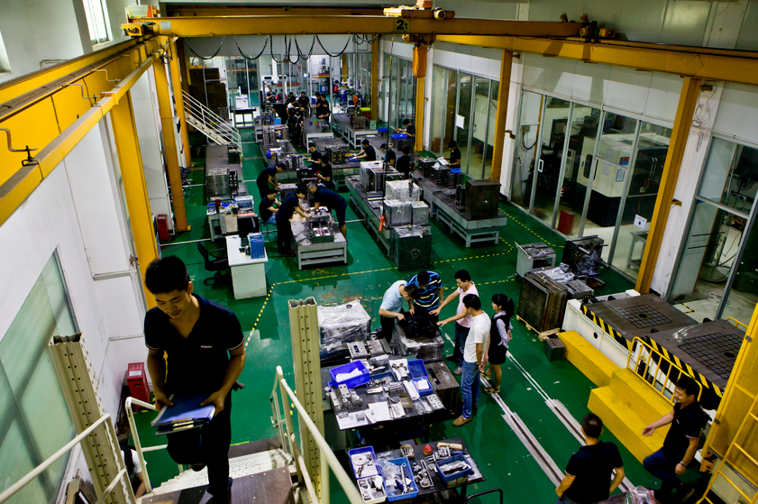 共享工厂内，几个创业同行在一起研究一个产品模具，身后共享的机器设备和生产工人正在忙碌。