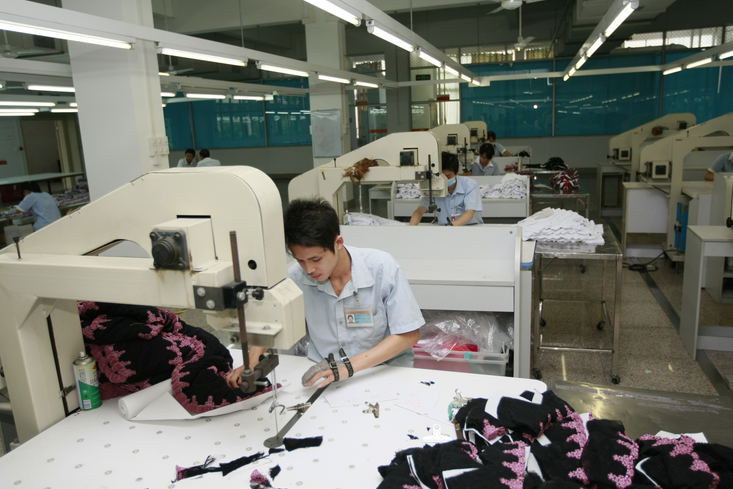 工人们正在电动裁剪机前工作。