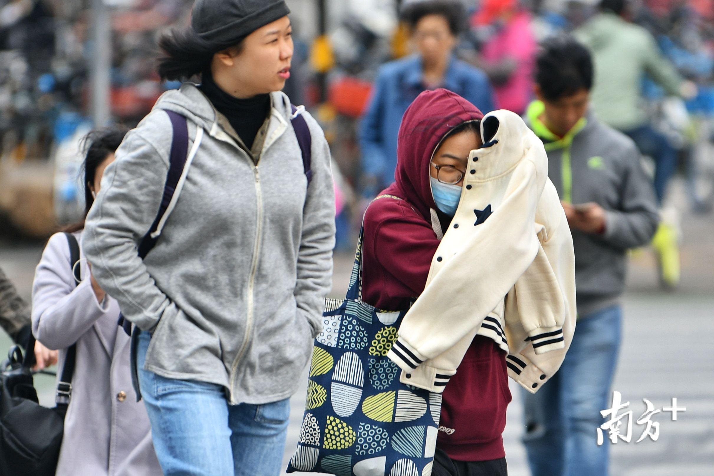 佛山街头,凛冽寒风吹得上班的市民连忙利用外套阻挡.