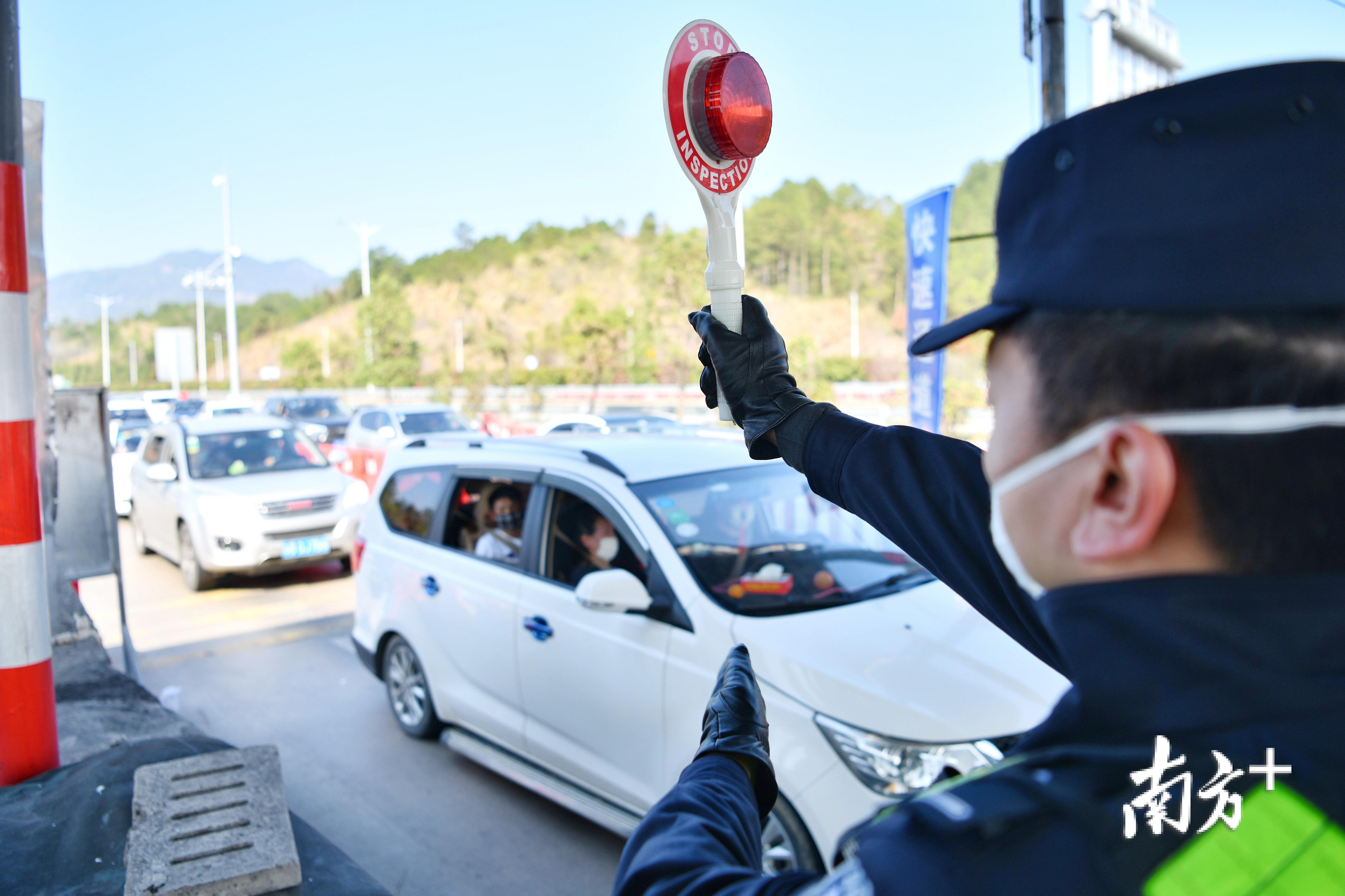 民警举起示意牌提醒过往车辆停车接受检查. 记者 曾亮超 摄