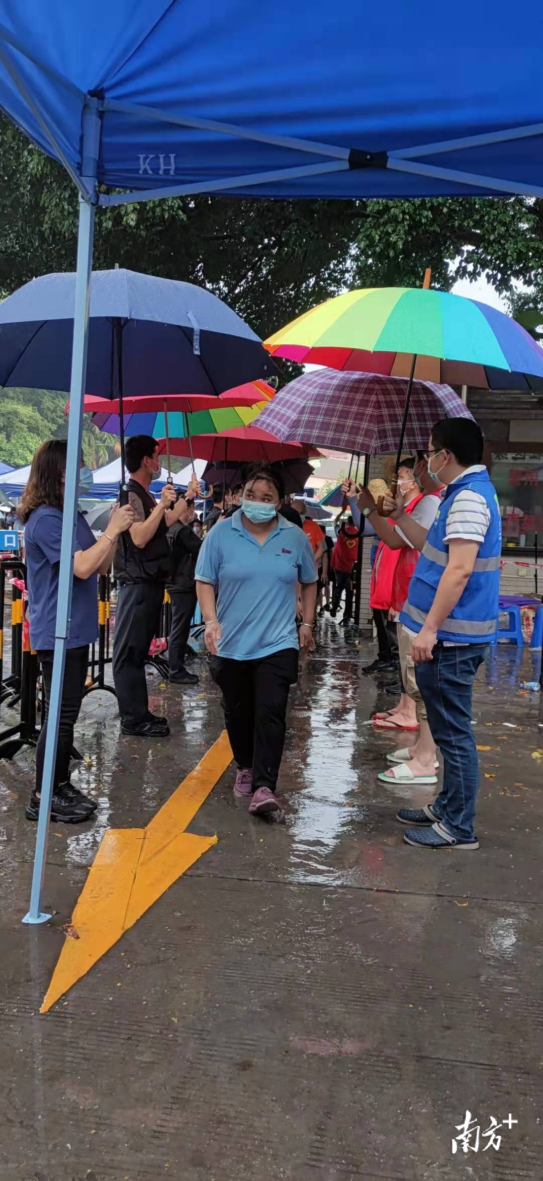 大雨中,梅塘社区核酸检测采样点党员用雨伞撑起为民通道.黄政正 摄