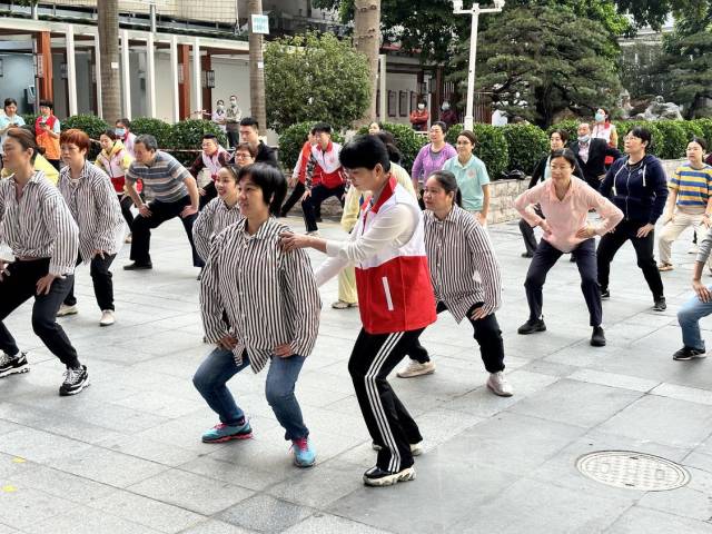 活动现场，志愿者为不熟悉八段锦标准动作的患者进行现场指导。