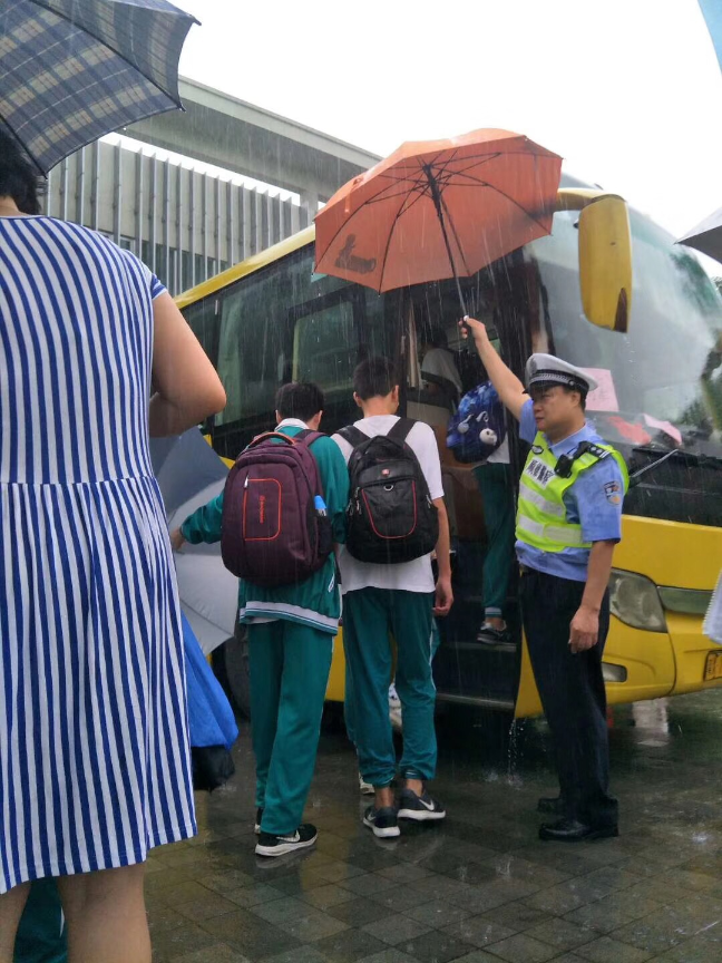 顺德交警麦业强将雨伞挡到了学生的头顶，自己的衣服却被雨淋湿了。 