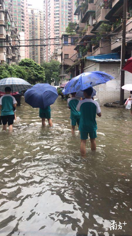 广州第五中学的学生借用药科大学课室上课，放学了，他们在积水中跋涉。