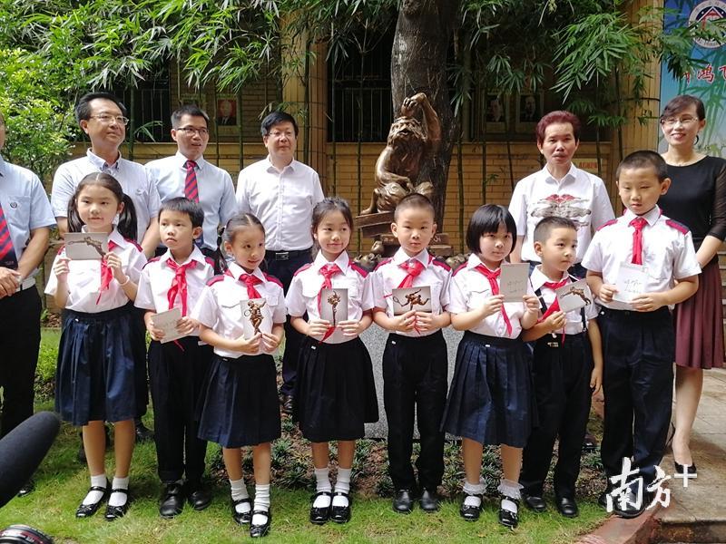 许鸿飞和东山培正小学师生在《猴顿苹果》前合影留念。