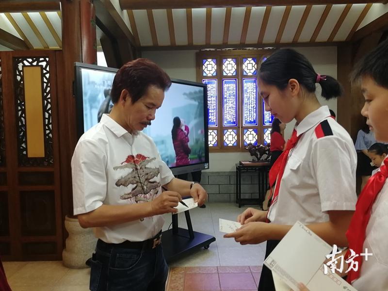 孩子们簇拥着许鸿飞索要签名，对雕塑展现出浓烈的兴趣。