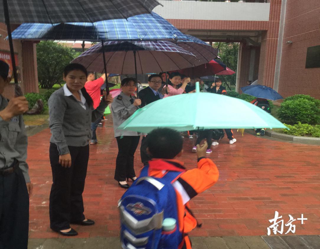 增城开发区小学内，学校校长和老师为学生撑起“伞路”。受访者供图
