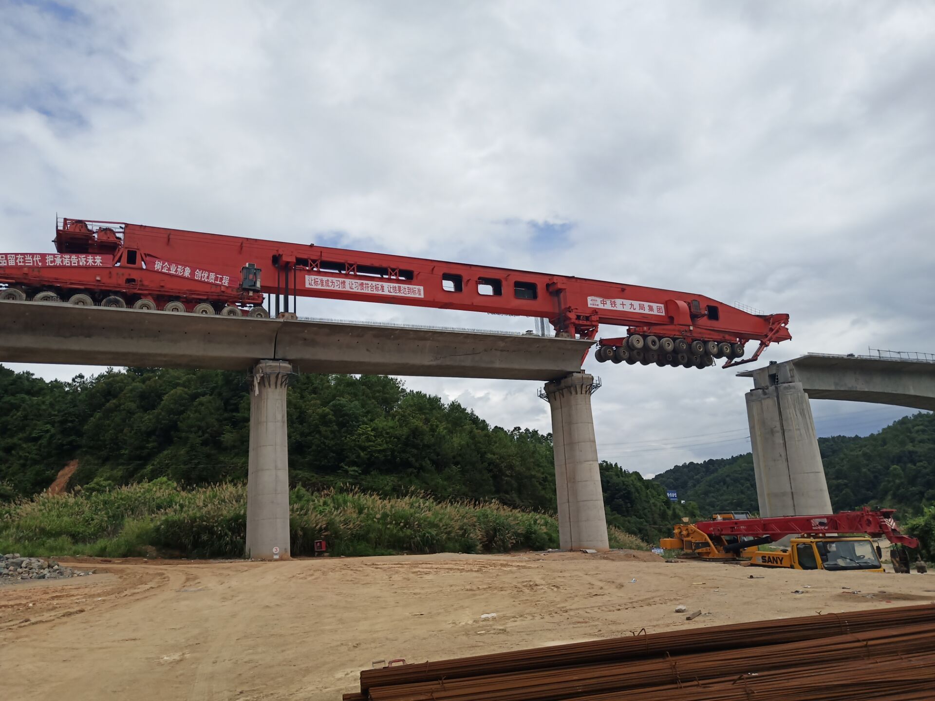 架设一孔700多吨的箱梁,需要过孔、喂梁、落梁、对位、灌浆等工序一步一步环环相扣、有条不紊进行。图为架梁机正在喂梁。 架设一孔700多吨的箱梁,需要过孔、喂梁、落梁、对位、灌浆等工序一步一步环环相扣、有条不紊进行。图为架梁机正在喂梁。