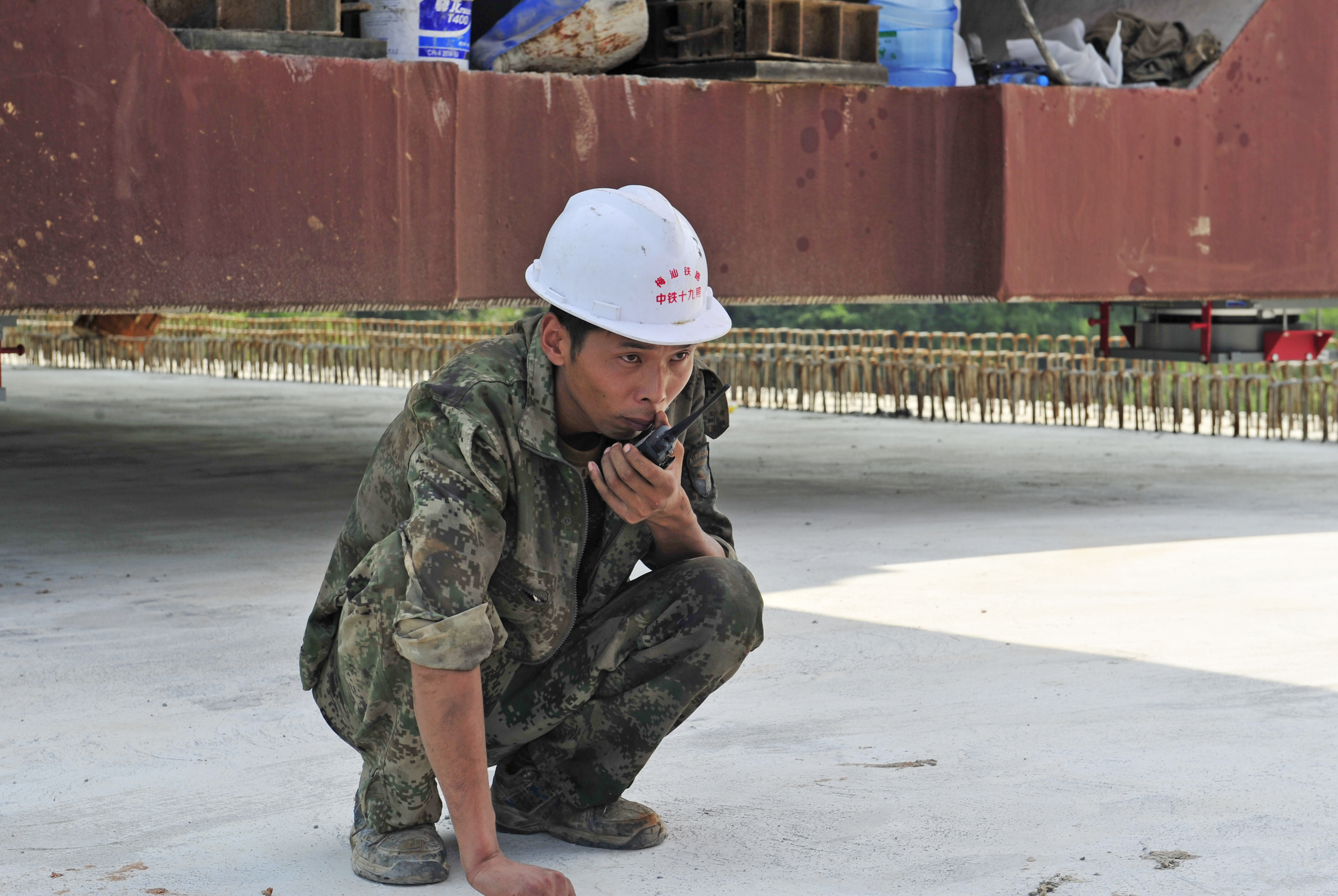 随着架梁缓缓移动,指挥人员一边拿着对讲机,一边注视着机器的运转。此时,另一个桥墩上的高铁工人蹲在,也在耐心地等待着架梁移动、对位。 随着架梁缓缓移动,指挥人员一边拿着对讲机,一边注视着机器的运转。此时,另一个桥墩上的高铁工人蹲在,也在耐心地等待着架梁移动、对位。