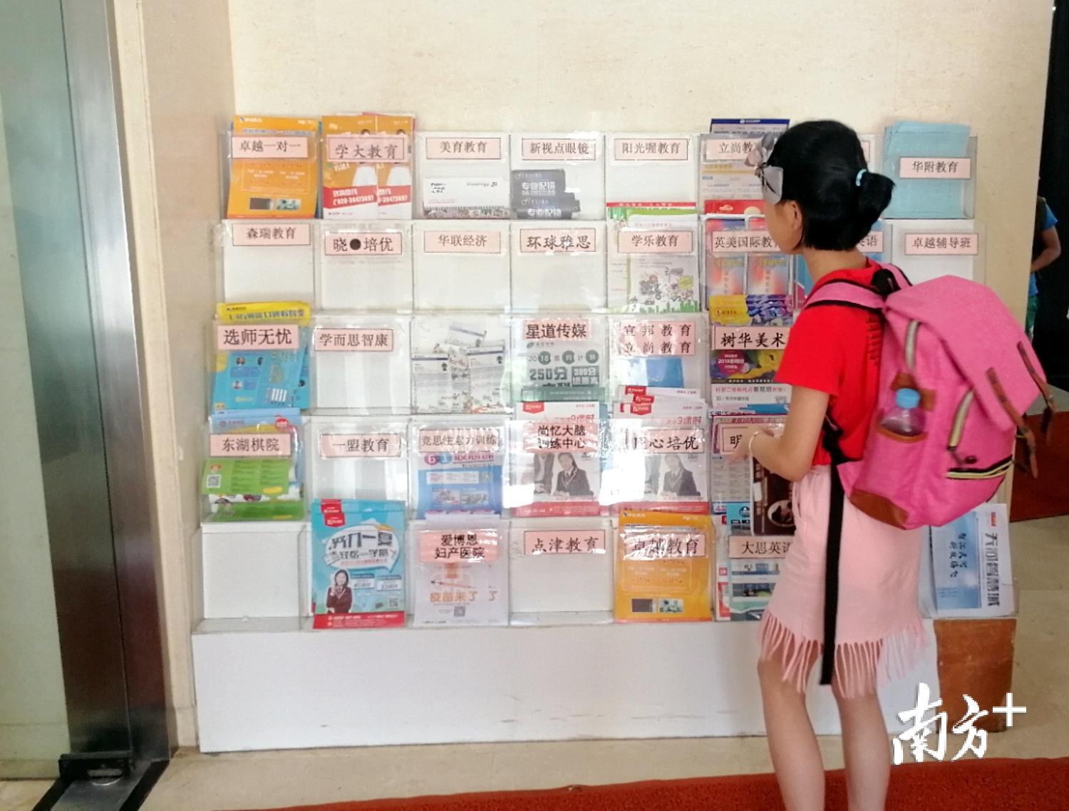 一名学生在华晟大厦一楼大堂驻足，观看各个培训机构的广告宣传单。