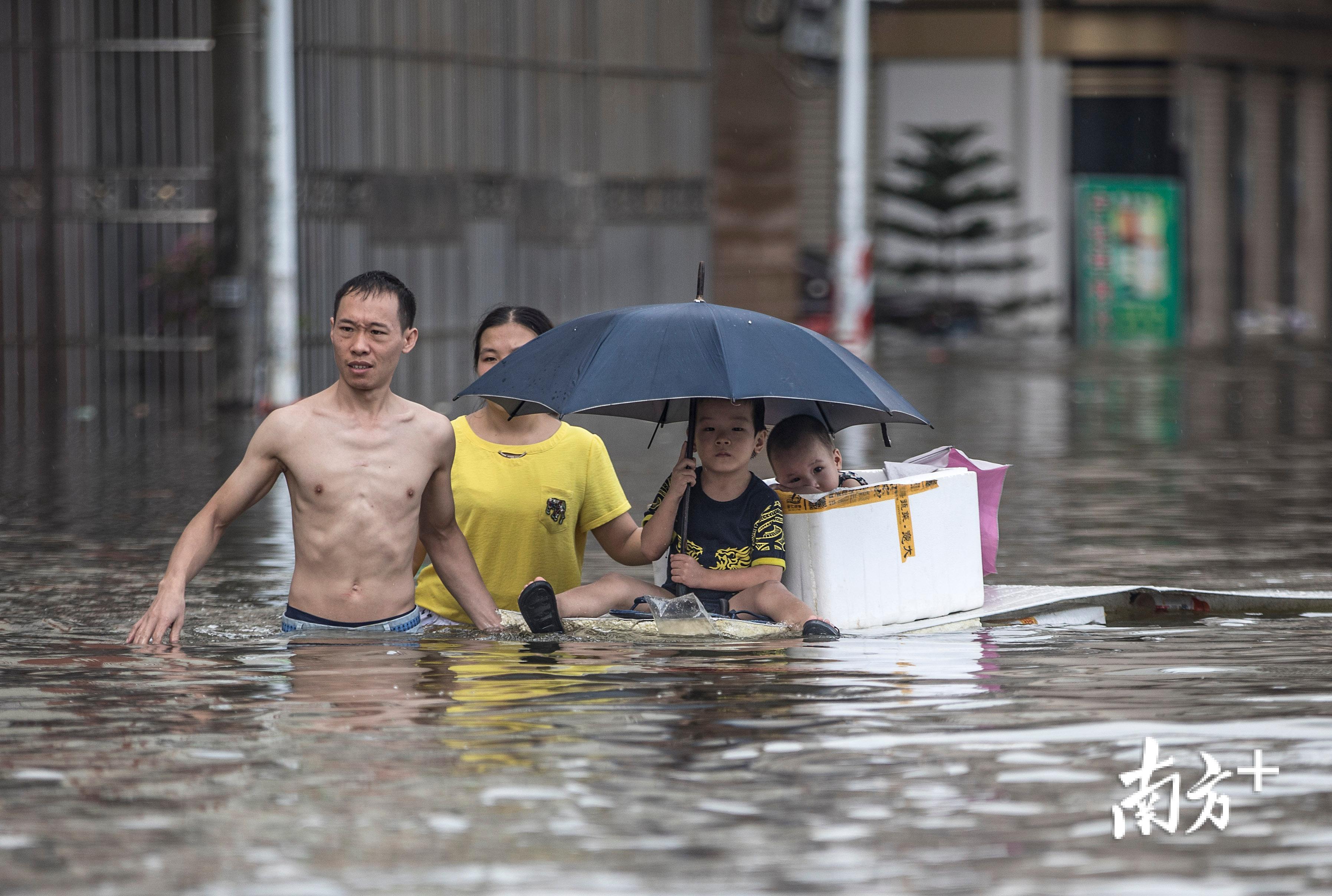△9月2日，陈贵路仍被洪水淹没，一对父母用简陋的木板运送孩子离开。