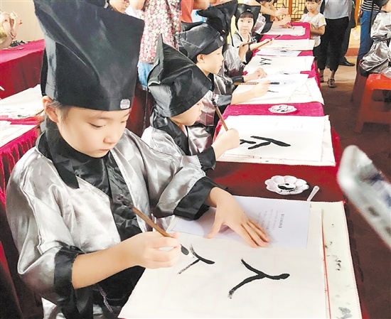 新会学宫,小学生在”开笔礼”上书写“人”字。 新会学宫,小学生在”开笔礼”上书写“人”字。