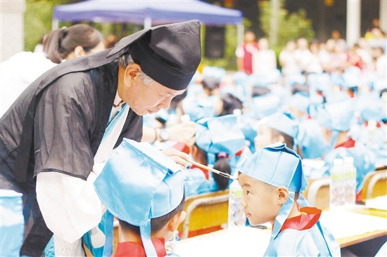 博物馆退休馆长梁炳尧给甘光仪学校的学生眉心点上红痣。 博物馆退休馆长梁炳尧给甘光仪学校的学生眉心点上红痣。