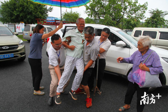 一位刚被转移的群众行动不便,众人上前帮忙。 一位刚被转移的群众行动不便,众人上前帮忙。