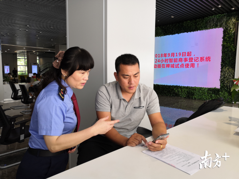 工作人员指导市民通过手机系统填写工商登记资料。