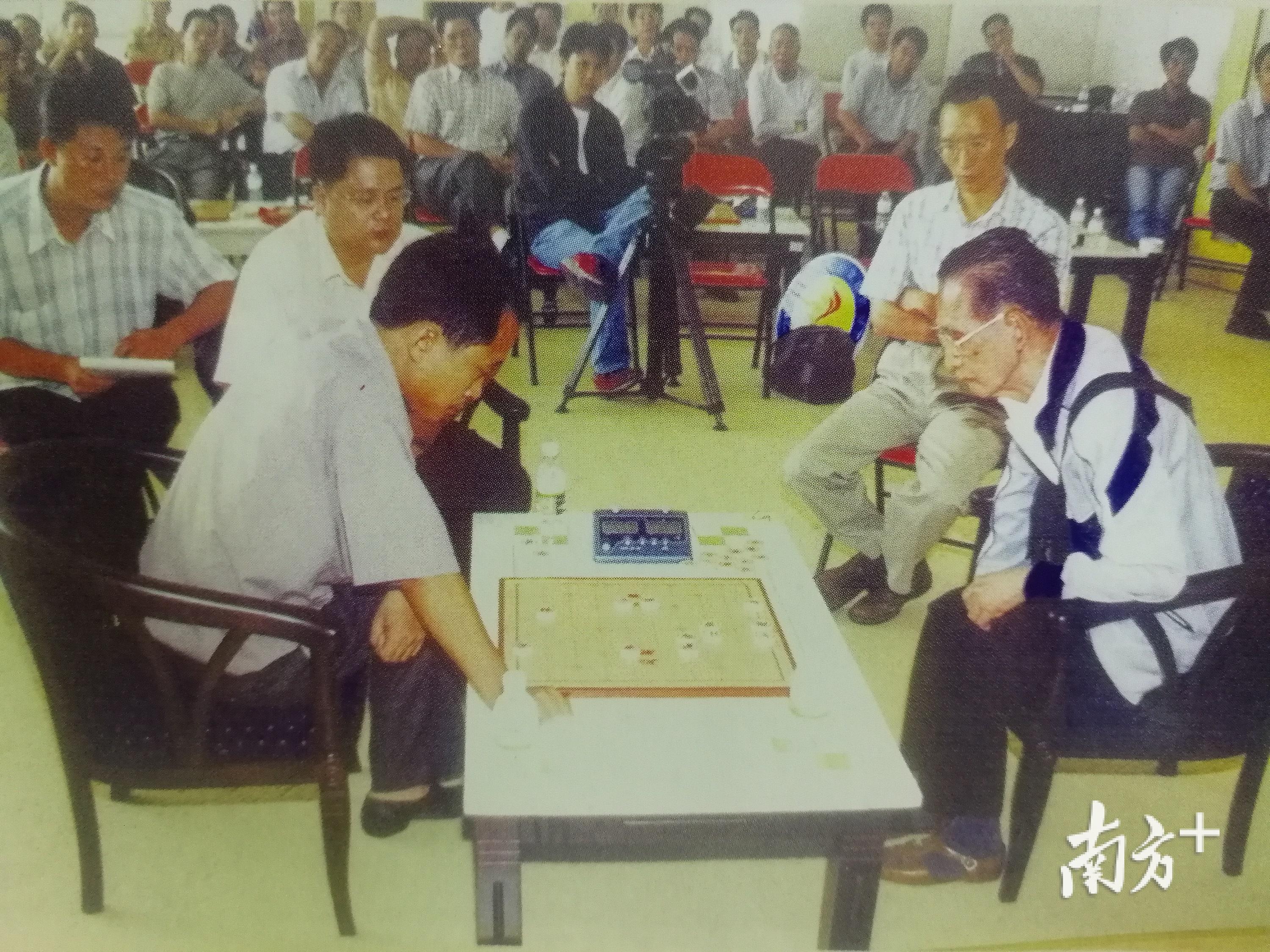2003年10月，在“杨官璘杯”象棋公开赛上，杨官璘（右）与选手对弈。（麦炜源 翻拍自《一代象棋宗师杨官璘》）