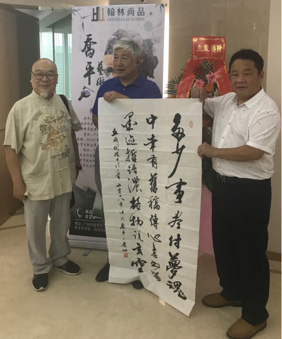 在王增丰大师(左一)见证下丘洪松主任(右一)从乔平大师(左二)手中接过书法作品。 在王增丰大师(左一)见证下丘洪松主任(右一)从乔平大师(左二)手中接过书法作品。