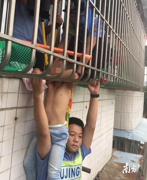 辅警叶荣东用肩膀托举起身体悬空在四楼防盗窗的小孩。高明公安供图