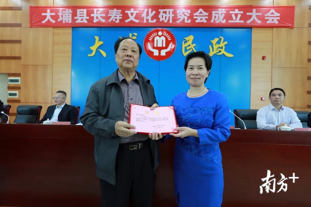 大埔县委常委、统战部部长张红梅为新当选会长袁光明颁发证书。