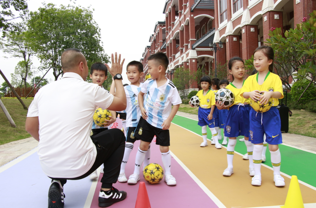 老师正在为准备上场踢足球的小朋友加油鼓劲。