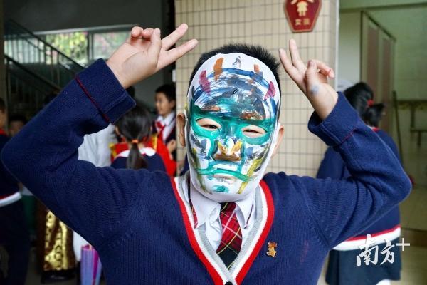 学生戴着自己完成的脸谱。