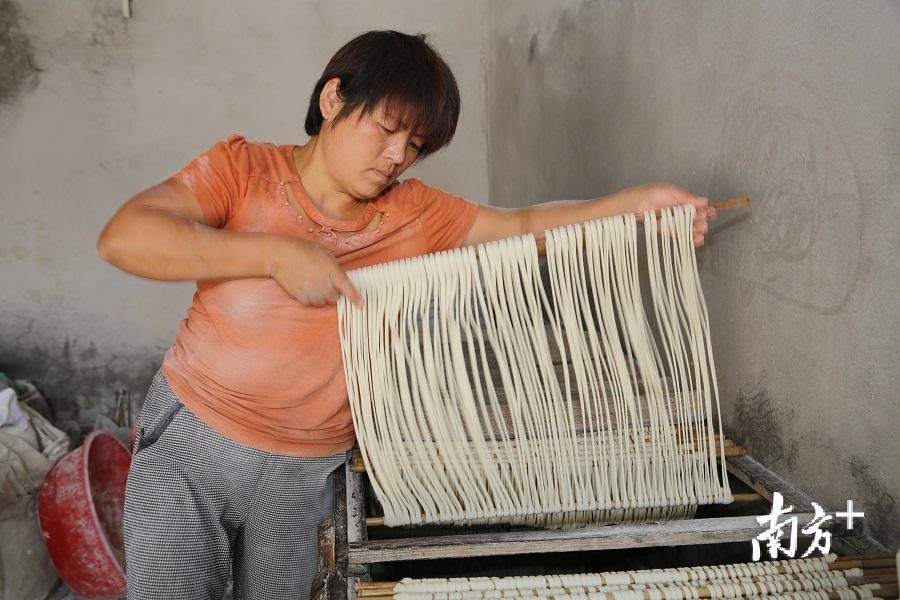 各握住两根面杆的一端，将面线往两边稍微撑长点，又沾些木茨粉，静置在面柜上“醒面。（胡金辉 摄）
