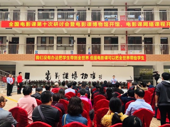 电影课博物馆剪彩现场，上方是条幅：“我们没有办法把学生带到全世界，但是电影可以把全世界带给学生。”