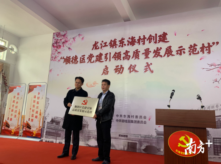 顺德区委副书记、政法委书记王勇向东海村党委书记左新明授予“顺德区党建引领高质量发展示范村”的牌匾。南方+记者 欧阳少伟 摄