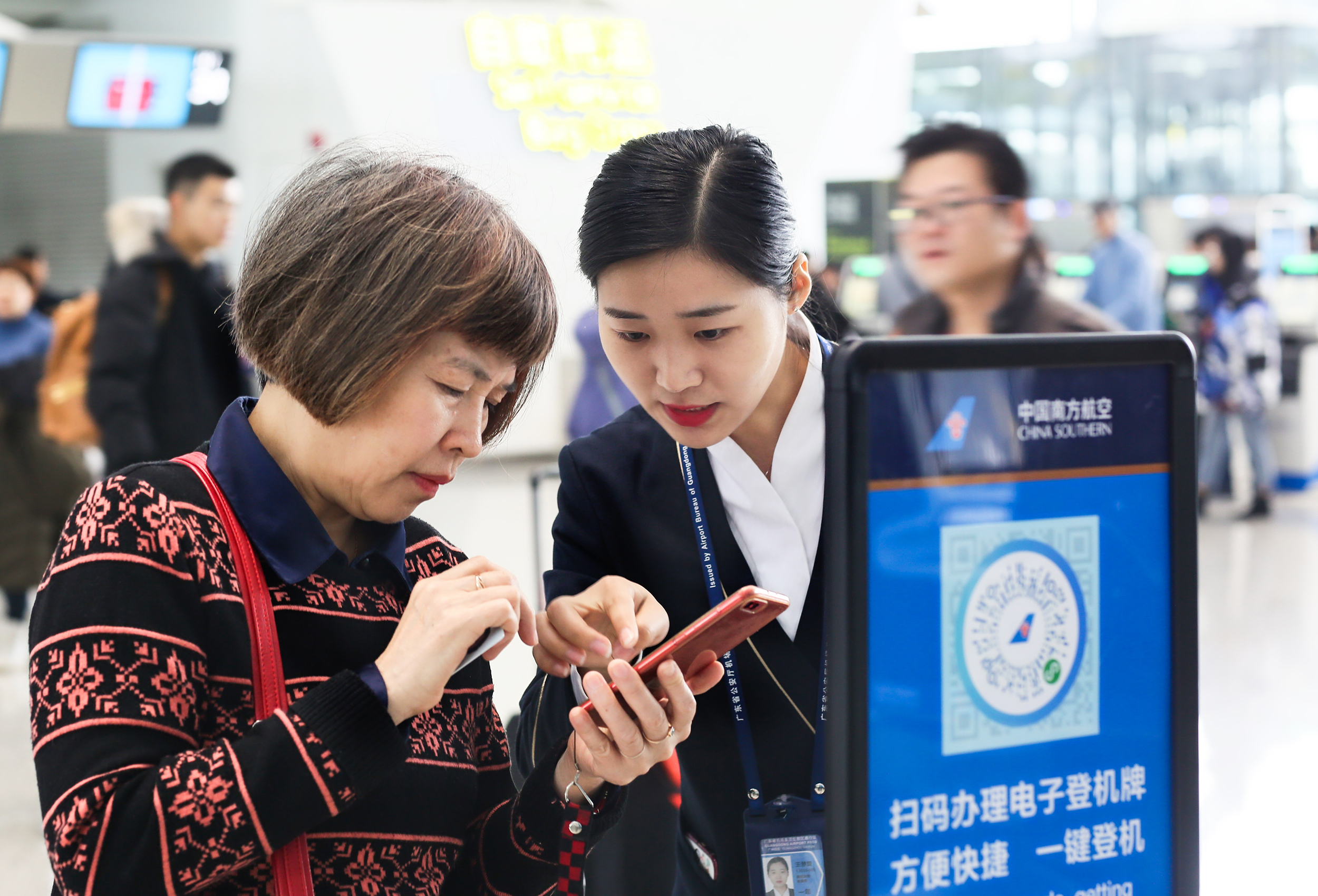 机场工作人员帮助游客使用电子登机牌张丽 摄