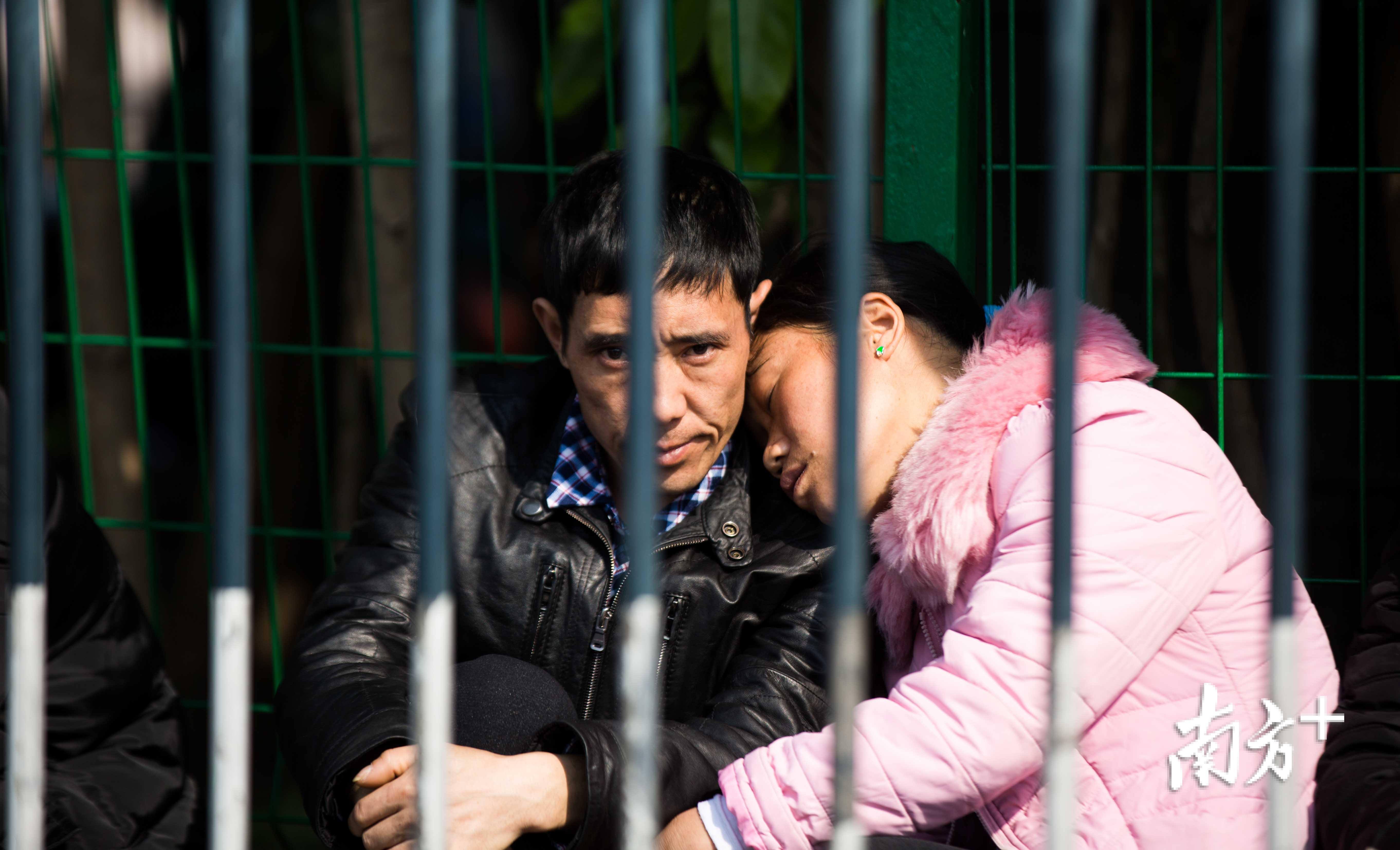 火车站前广场上，一名女子正靠着自己丈夫的肩膀上小憩。