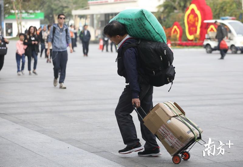 一位乘客手拉行李箱,肩扛满满的麻袋