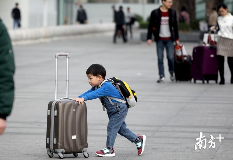 懂事又帅气的小朋友推着行李箱走向进站口.