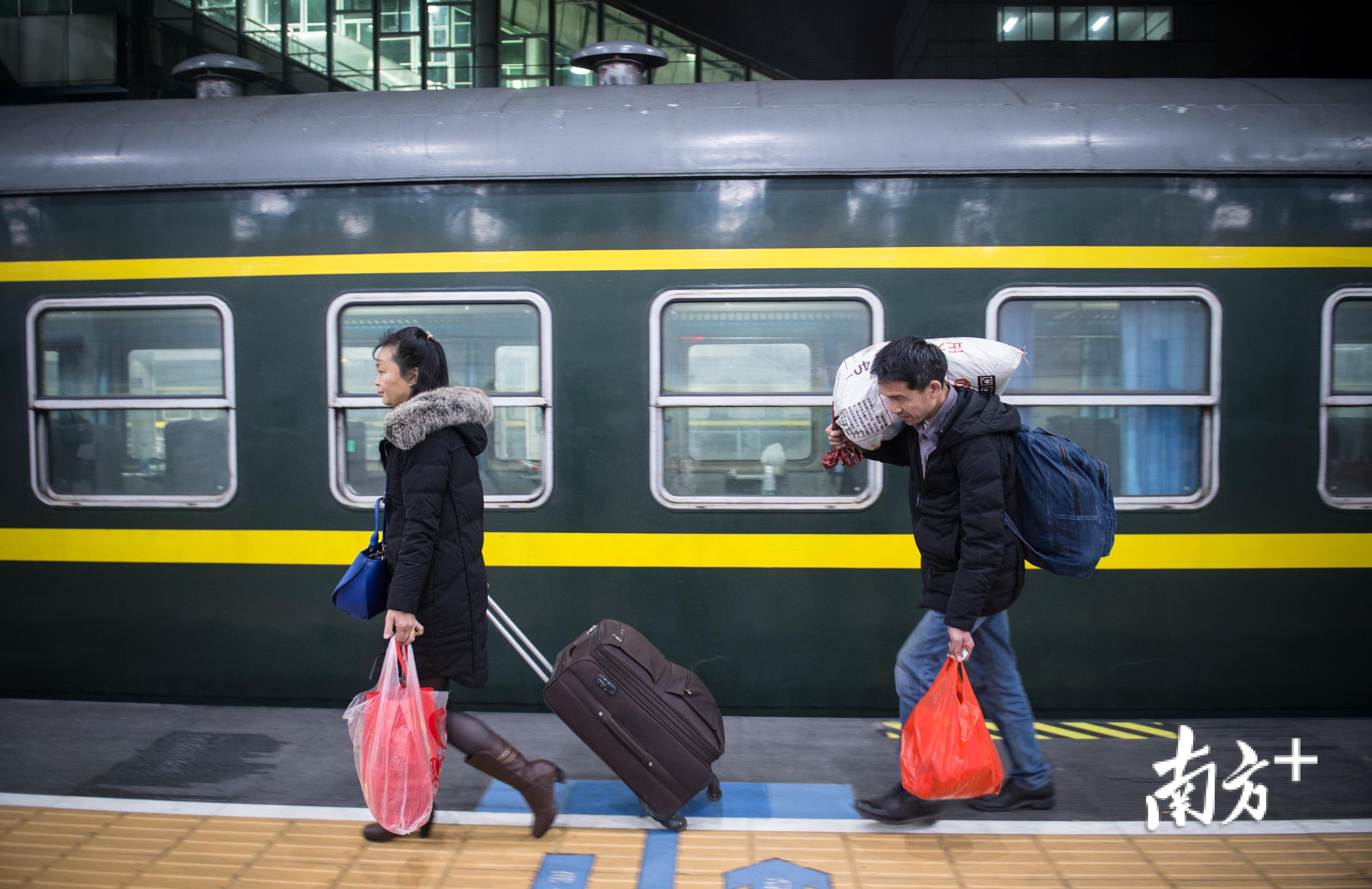 △22日凌晨3点18分，返岗专列到达广州东站，吴仁明和妻子扛着行李走下列车。