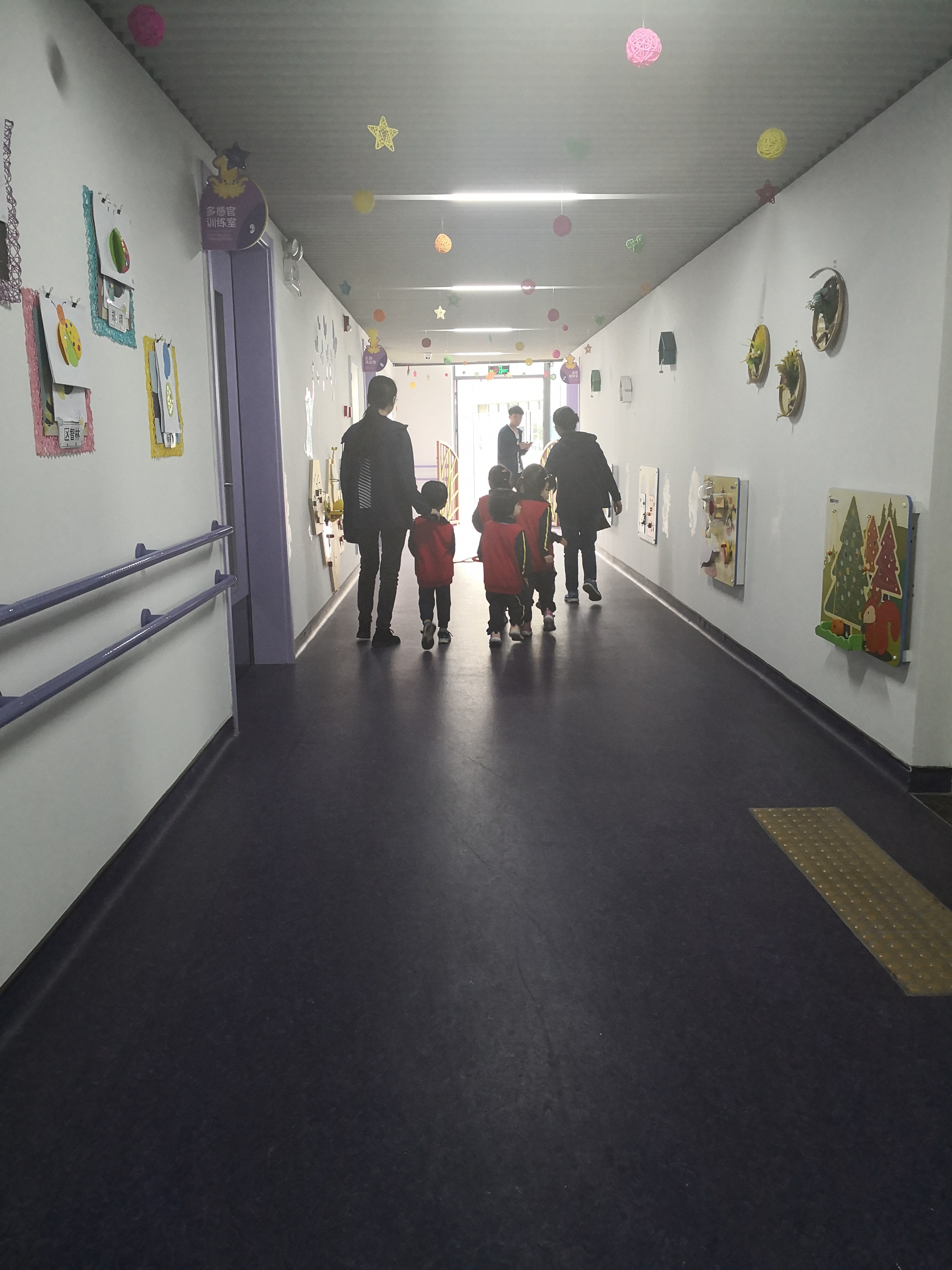 因为经常被其他事物吸引，无法像正常孩子一样排成一列，所以康复中心的老师们发明了这条牵引绳，让孩子们可以牵着绳子排成一队。图为孩子们结束了上午的课程，排队去吃午饭。