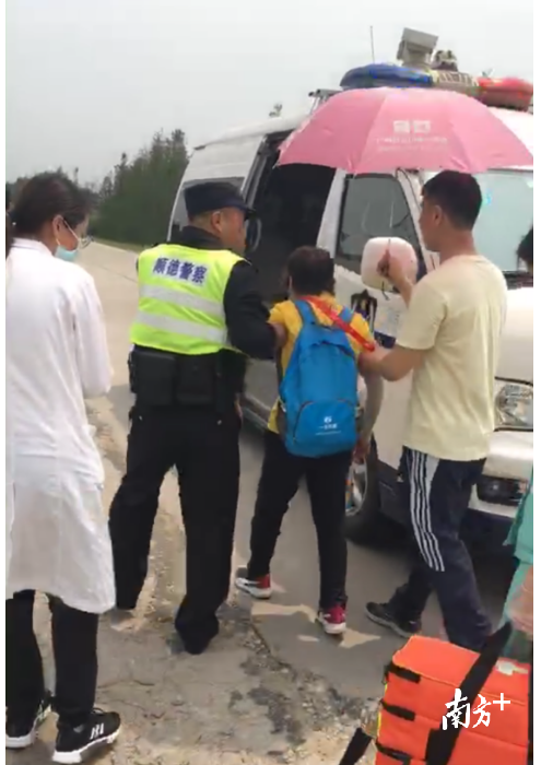 民警从执勤岗点取来矿泉水和遮阳伞，待婆婆身体状态好转后将其扶往警车并送至附近徒步医疗点进一步治疗。