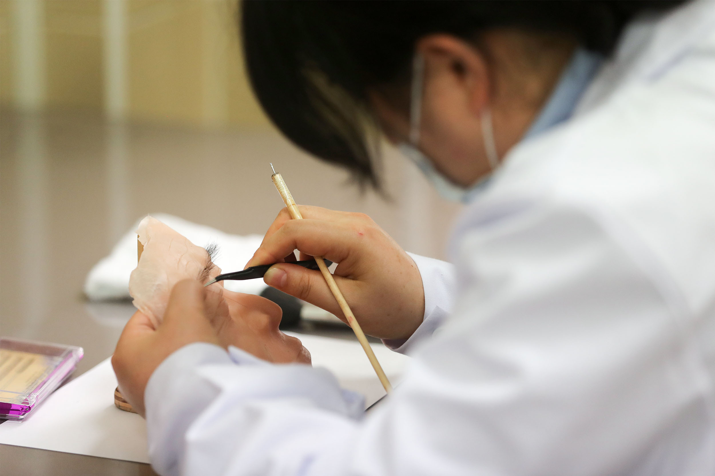 根据需求，遗体修复师在硅胶面皮上手工植入毛发、化妆等。