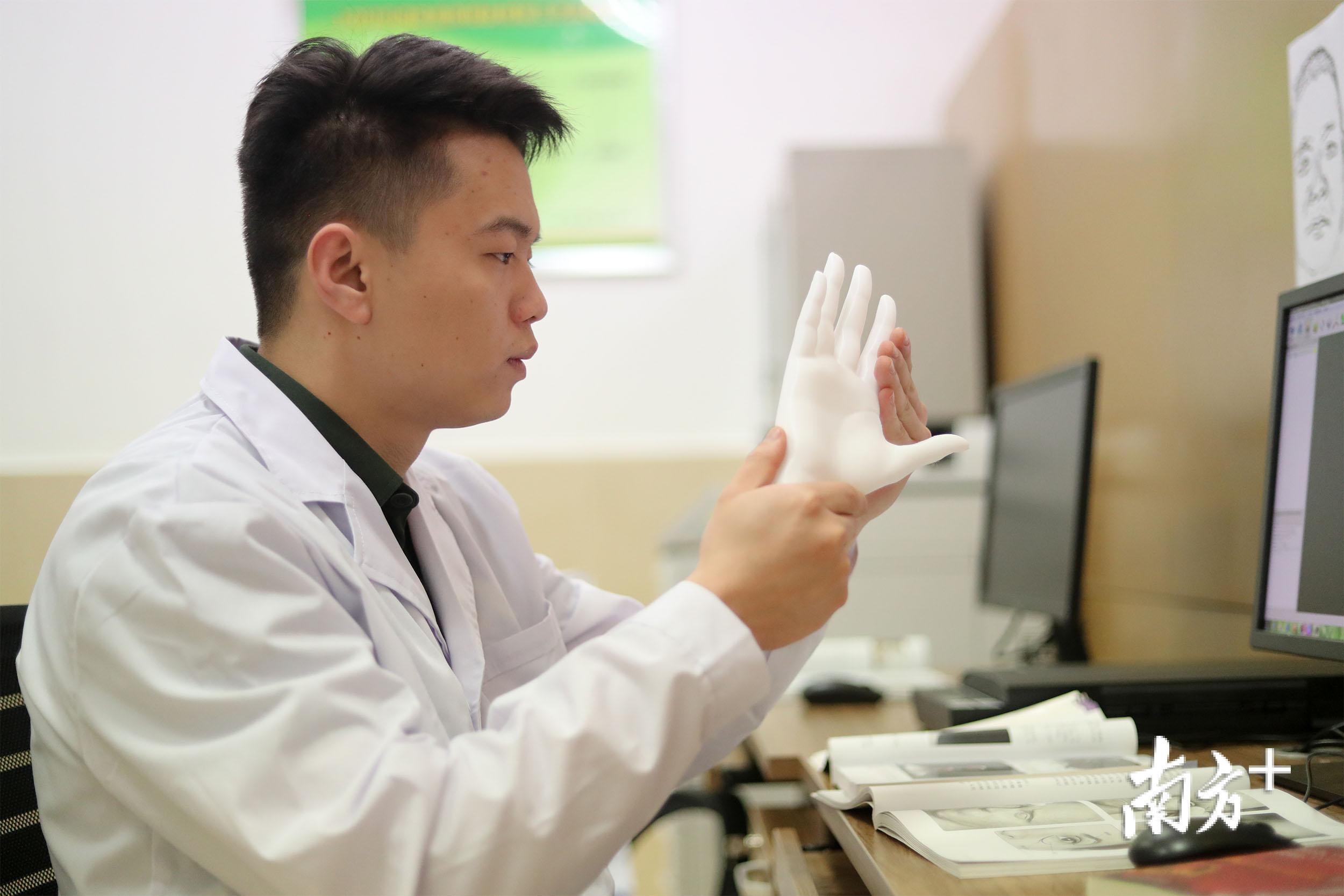 遗体修复师小刘拿着3D打印的手部模型。 