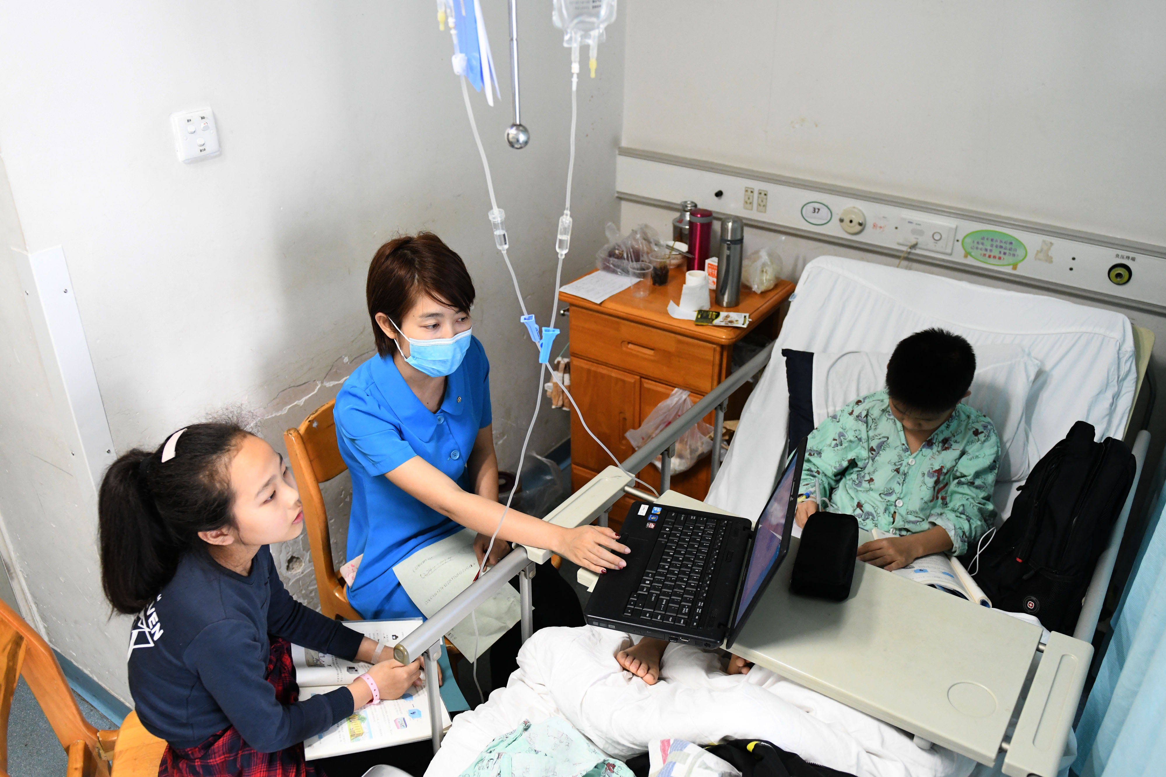 两位小朋友正在病房里的课堂上认真学习。