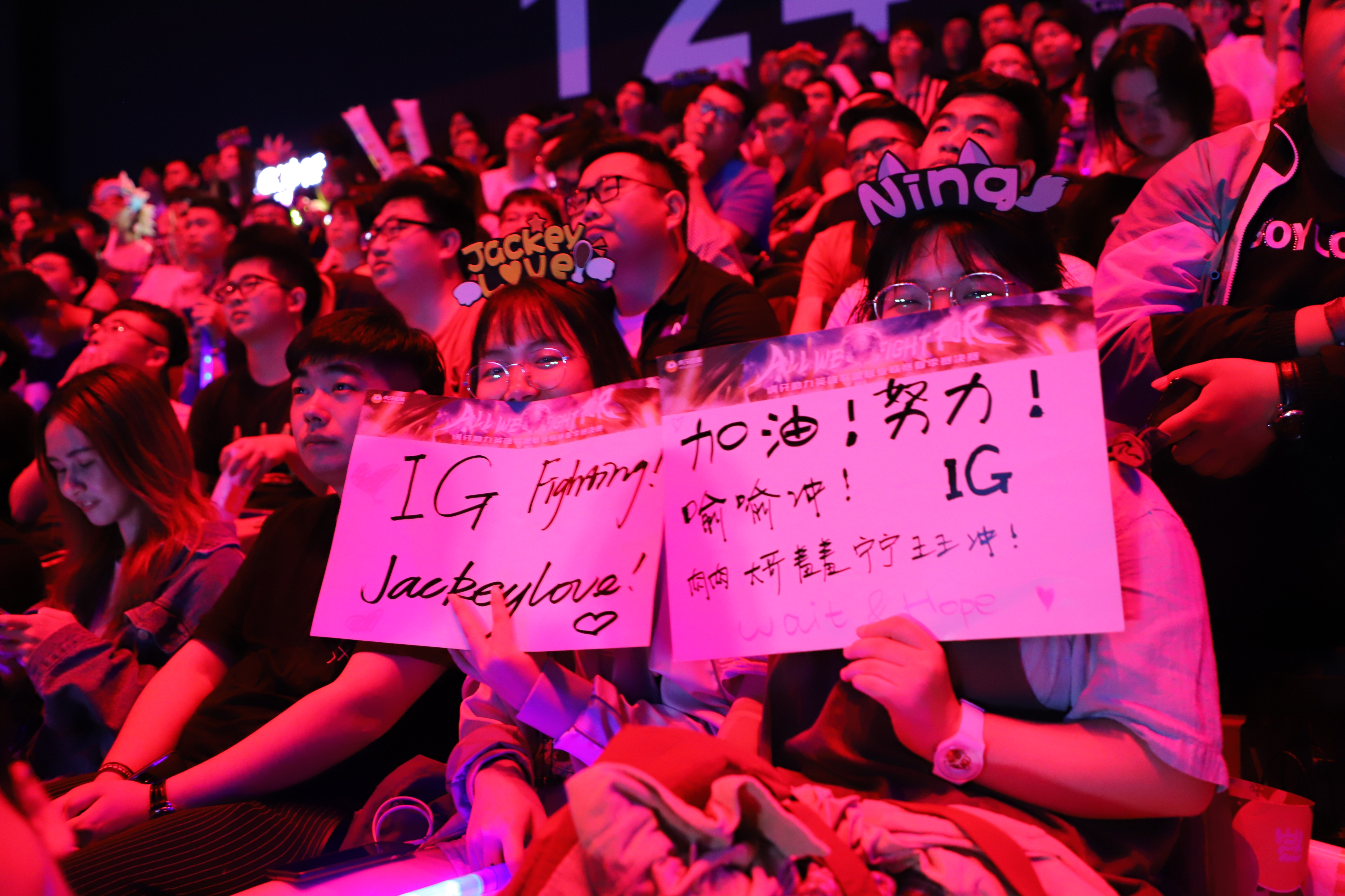 在看台上,几位ig的粉丝举着应援牌看比赛,眼里都是小星星!