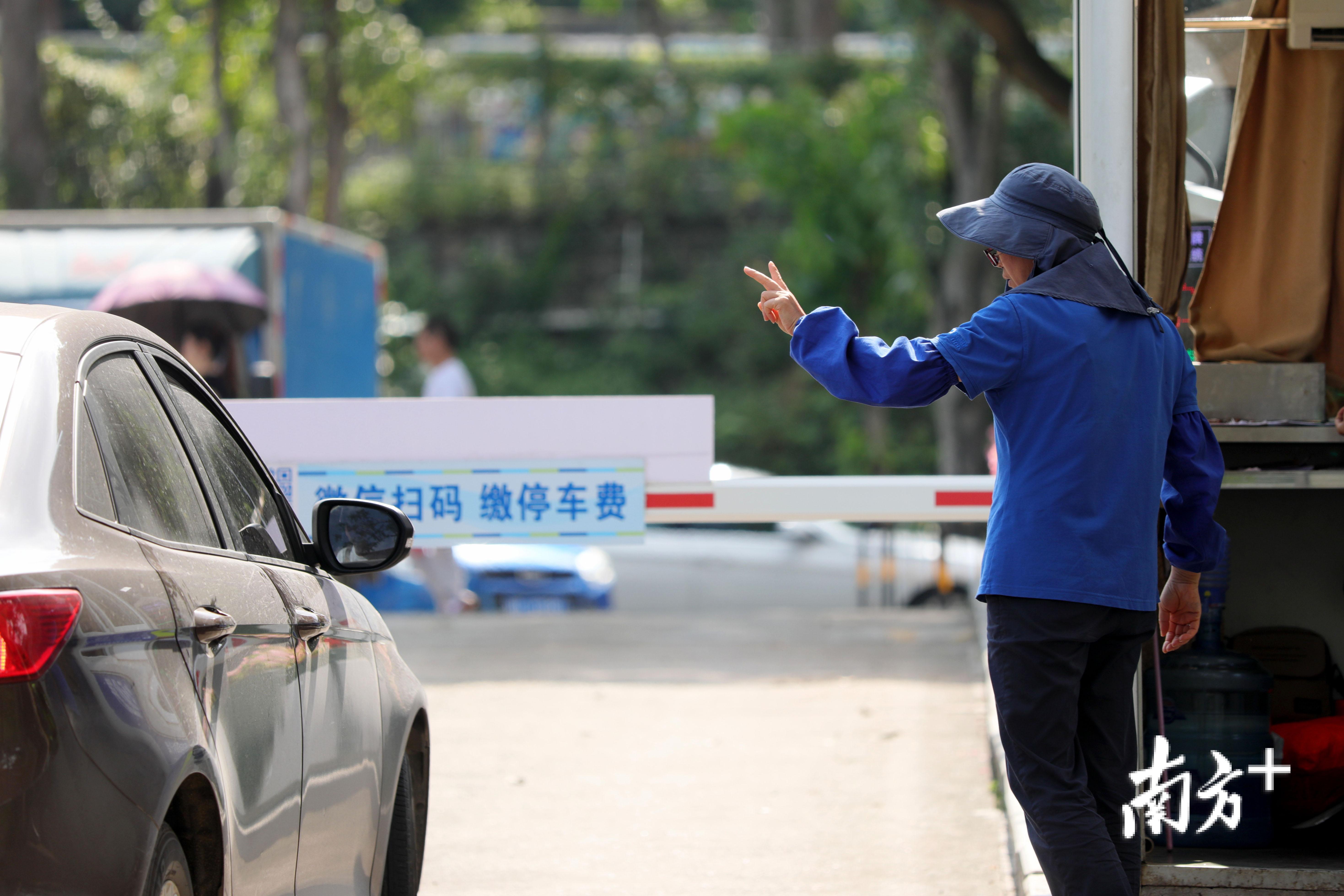 一名在户外停车场收费的管理员向车主比划着停车费.