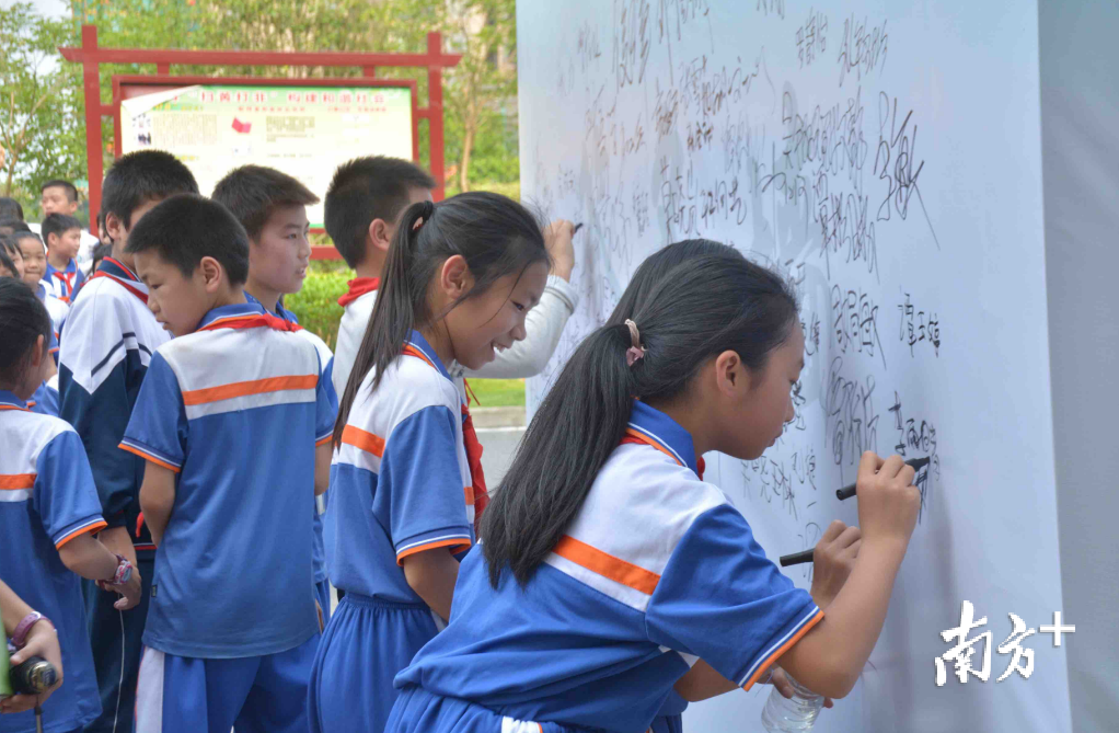 学生在签名墙上签名承诺参与“绿书签行动”。邓文燕 摄