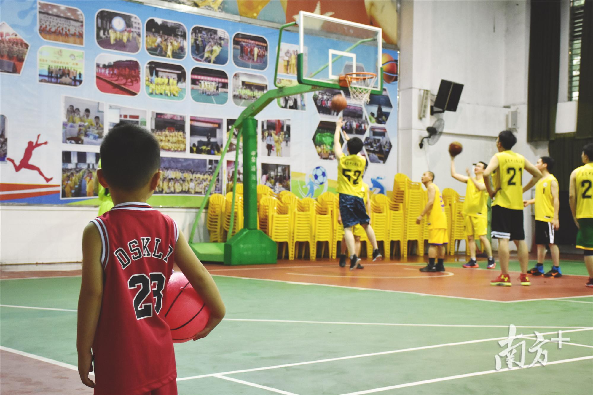 一位小朋友拿着篮球注视着父亲在球场的一举一动（万佩珊拍摄）