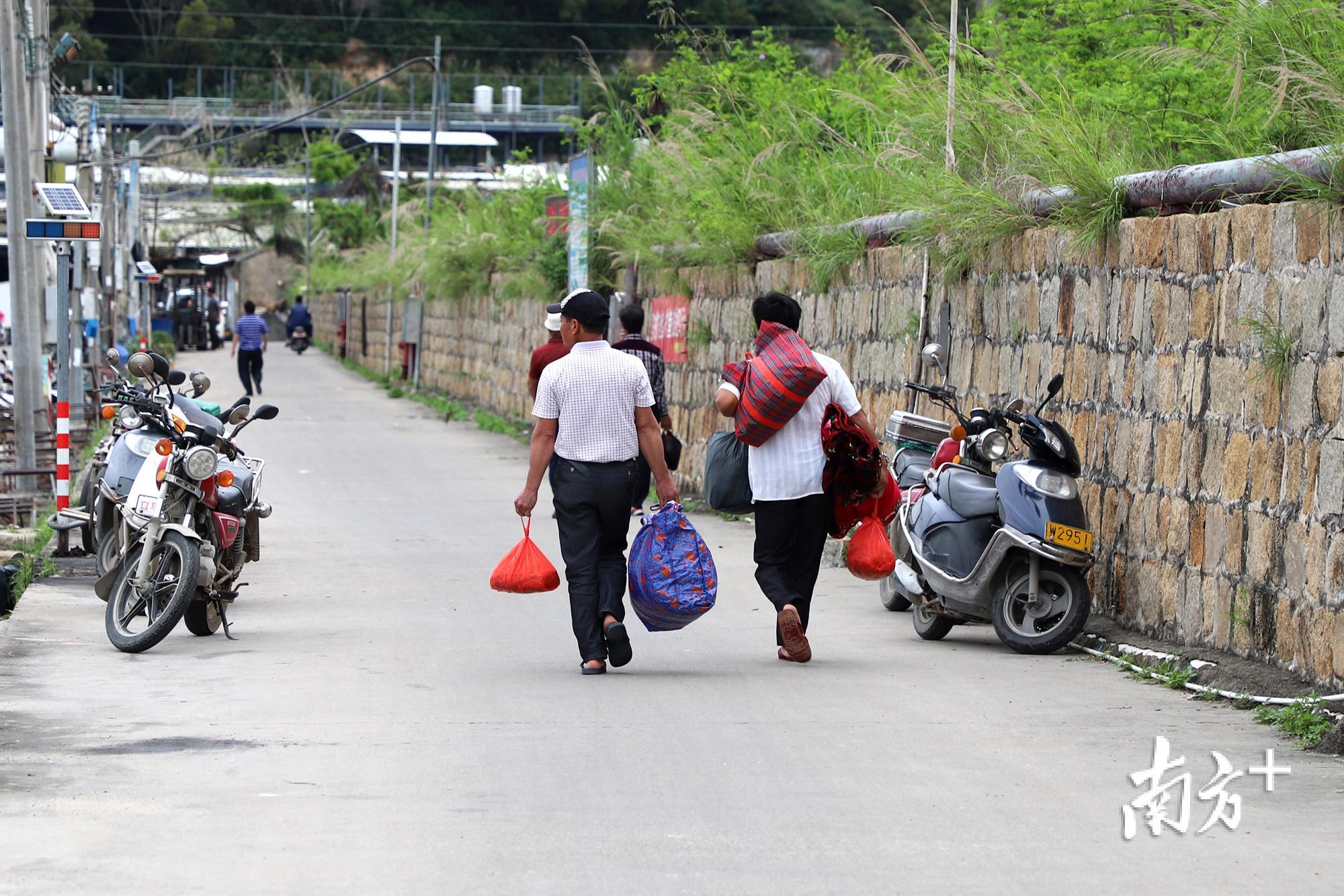 图为码头上背着行李准备回家的渔民。