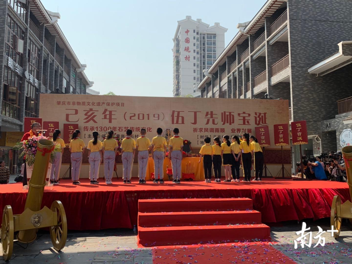 端州区黄岗小学的学生排成一列，对着“伍丁”坐像作揖行礼。