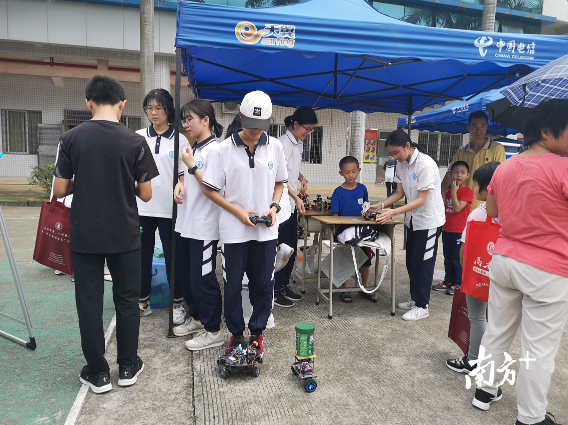 来自三水中学高二（18）班的雷心怡正在教初中的学弟学妹操作机器人。李周秦 摄