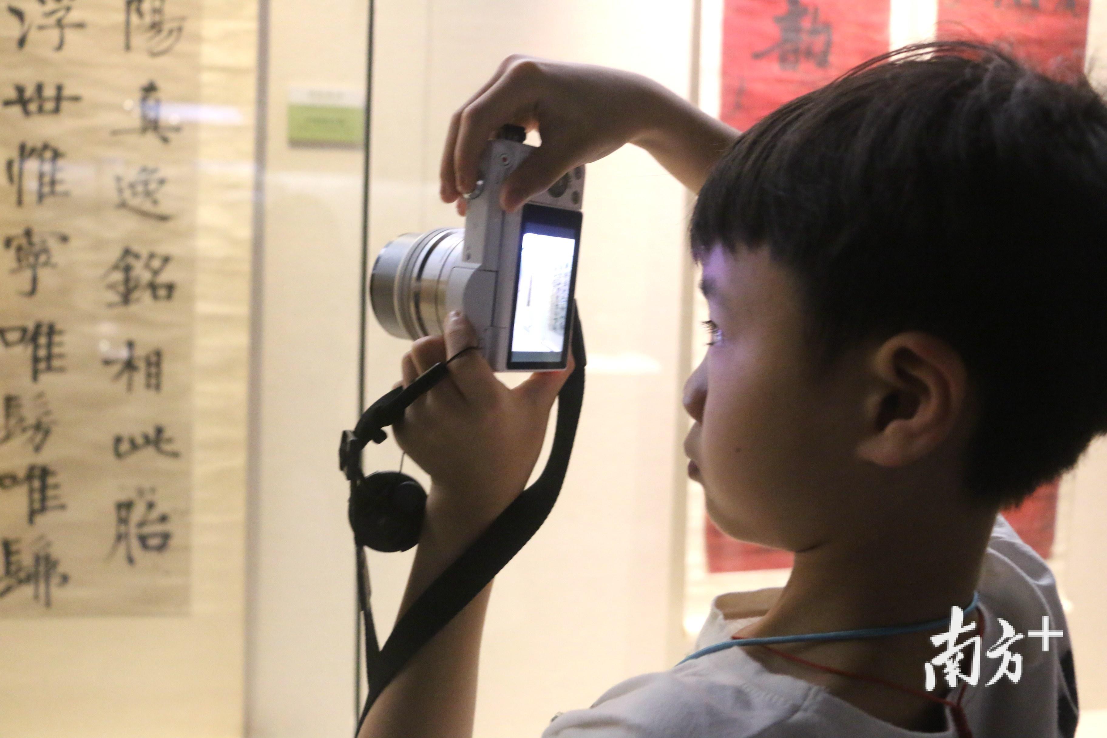 一位小朋友拿着照相机对着展品拍摄，表情严肃认真。张伟炜 摄