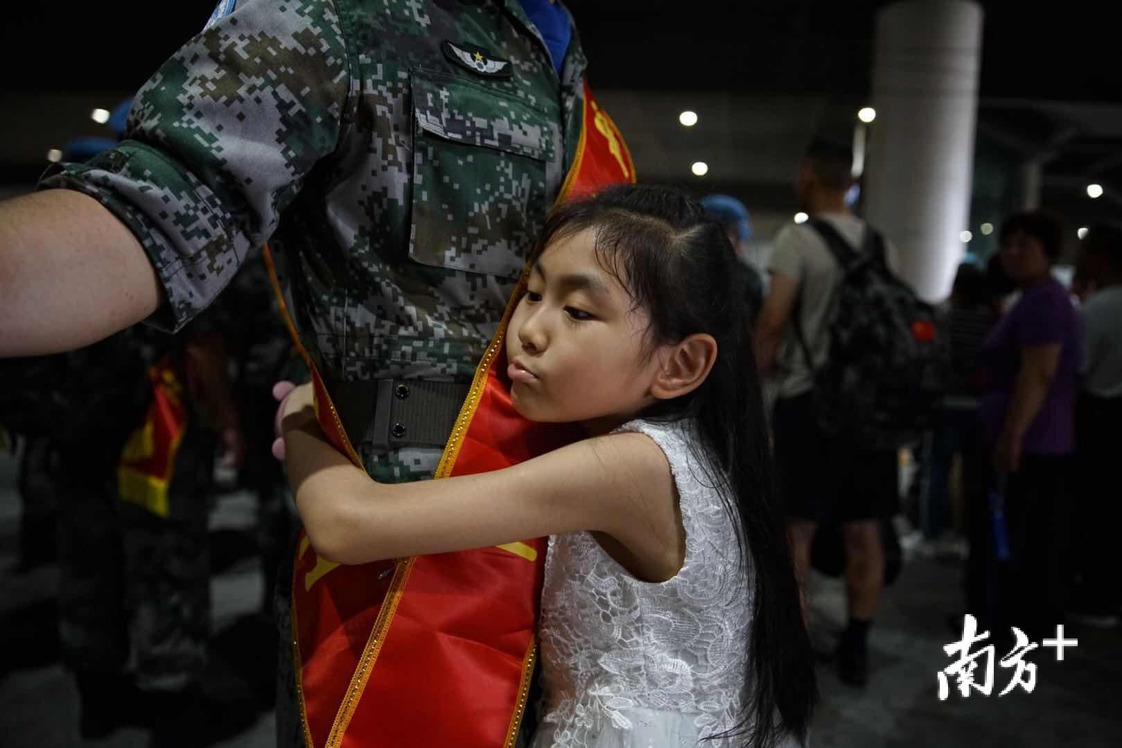 一名小女孩紧紧抱着即将离开她的爸爸.