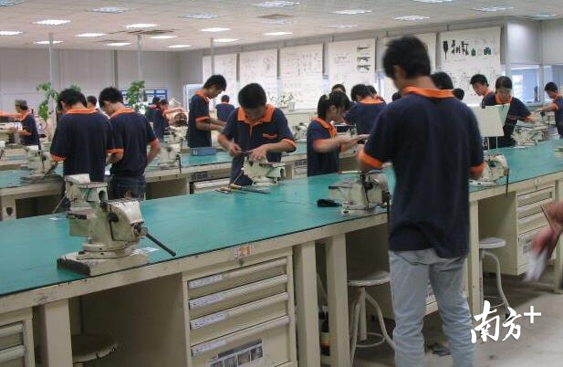 欧司朗钳工培训室内50多个培训工位依次排开，学生们正在进行实操练习。企业供图