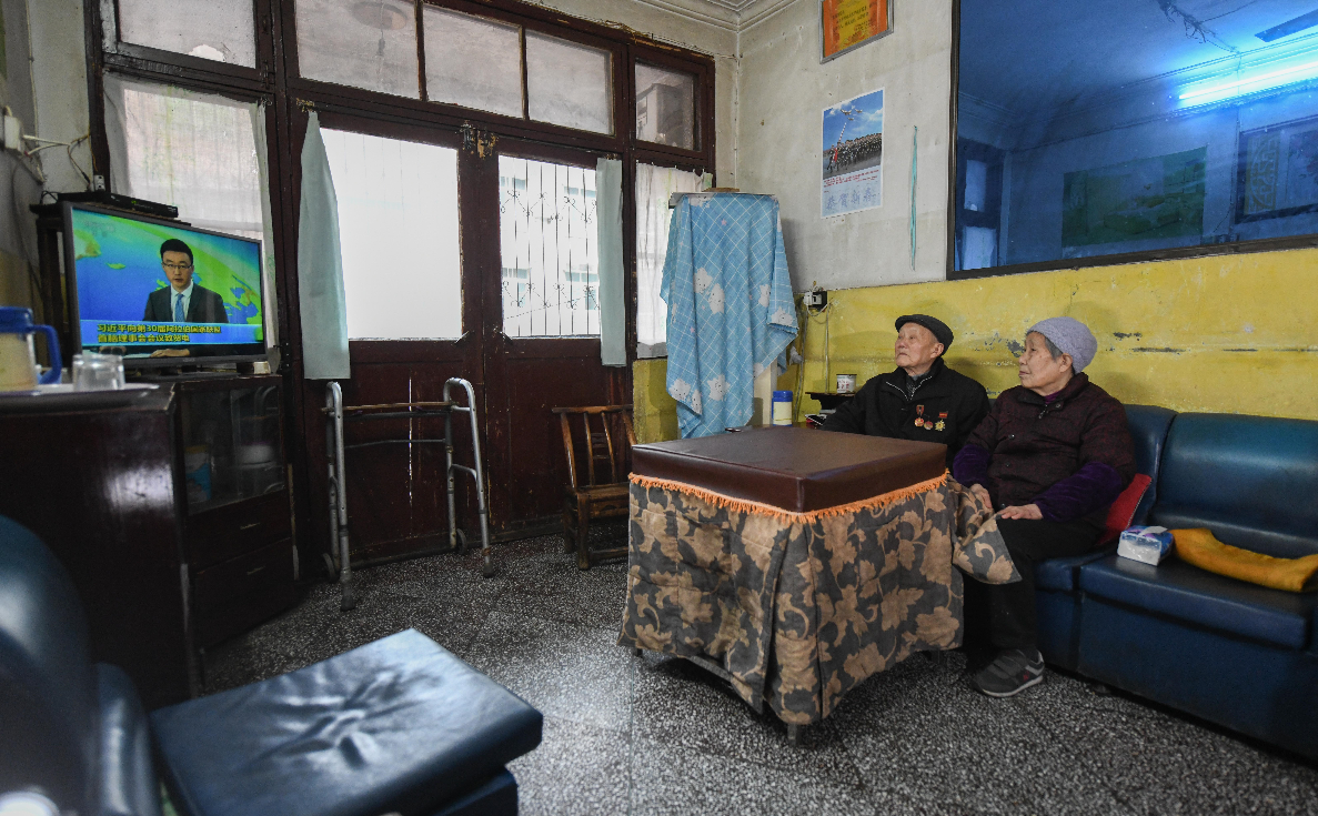 张富清和老伴在住了几十年的老房子里看电视。